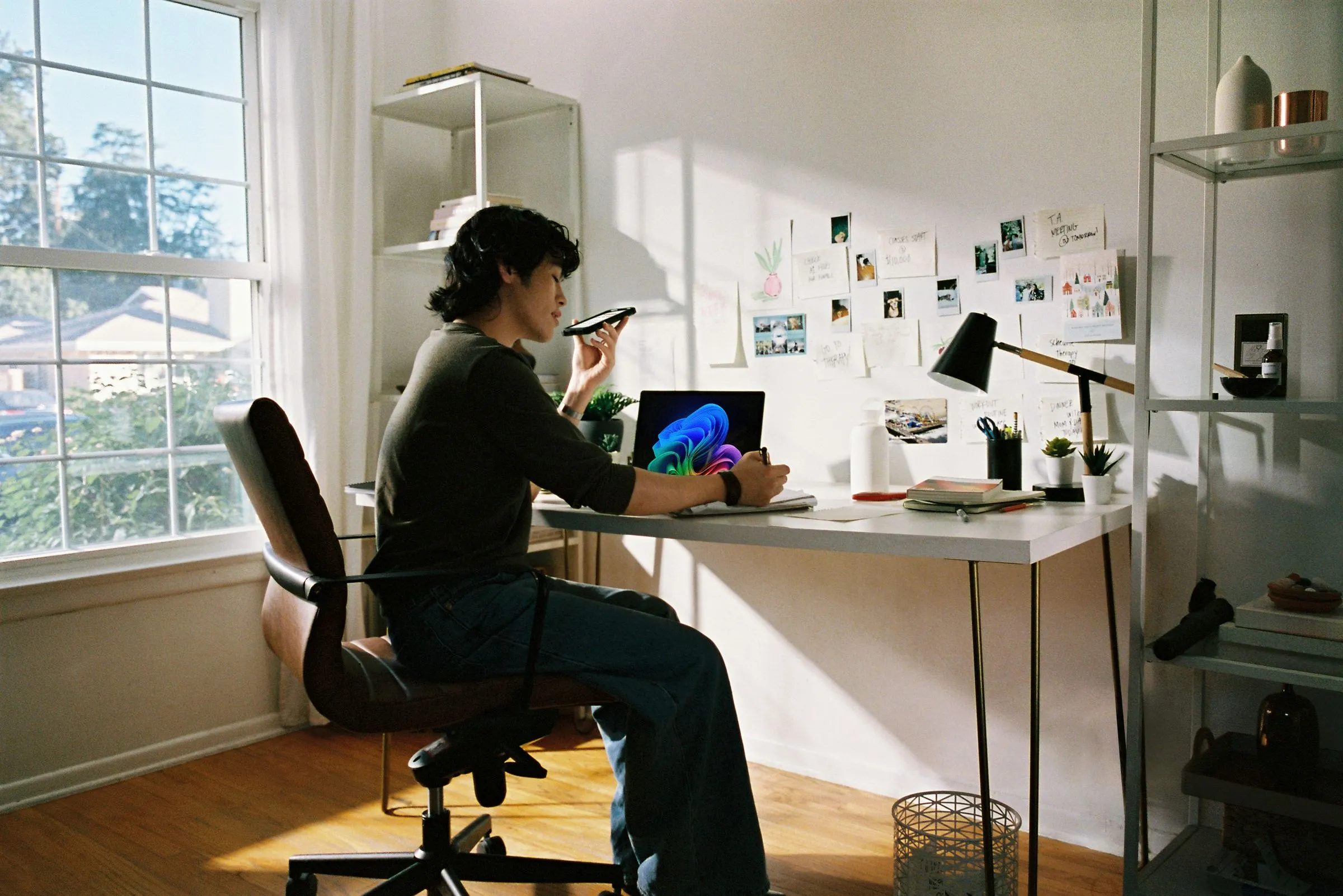 A district staff member at a desk by a window, on the phone, with a laptop open.